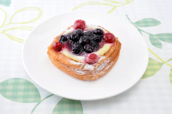 Pastel de arándanos con crema de natillas en un plato sobre un mantel — Foto de Stock