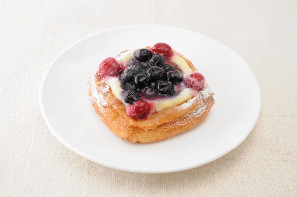 Pastel de arándanos con crema de natillas en un plato sobre un mantel — Foto de Stock