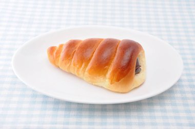 masa örtüsü üzerinde bir tabak üzerinde çikolata kornet tereyağı ekmek rulo