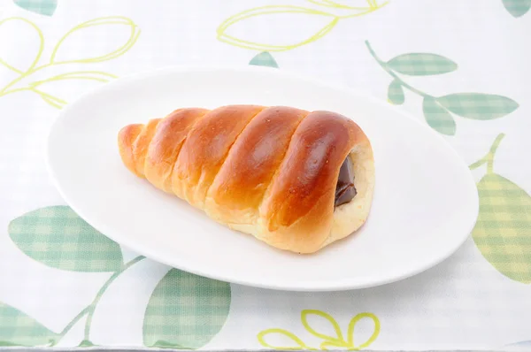 Chocolate cornet butter bread roll on a plate on table cloth — Stock Photo, Image