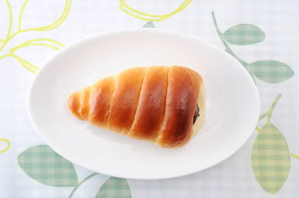 Rolo de pão de manteiga de corneto de chocolate em um prato na toalha de mesa — Fotografia de Stock