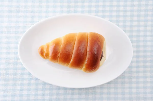 Chocolate cornet butter bread roll on a plate on table cloth — Stock Photo, Image