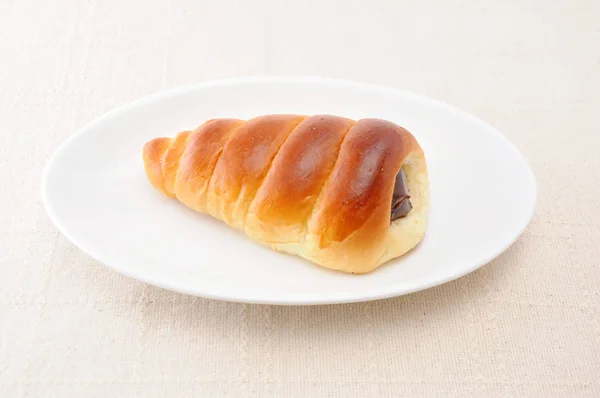 Chocolate cornet butter bread roll on a plate on table cloth — Stock Photo, Image