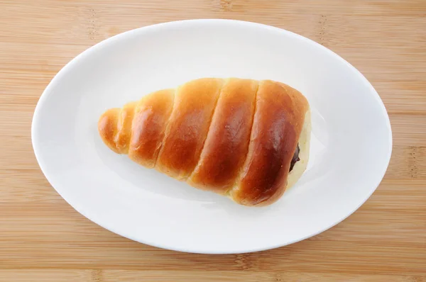 Chocolate cornet butter bread roll on a plate on table — Stock Photo, Image