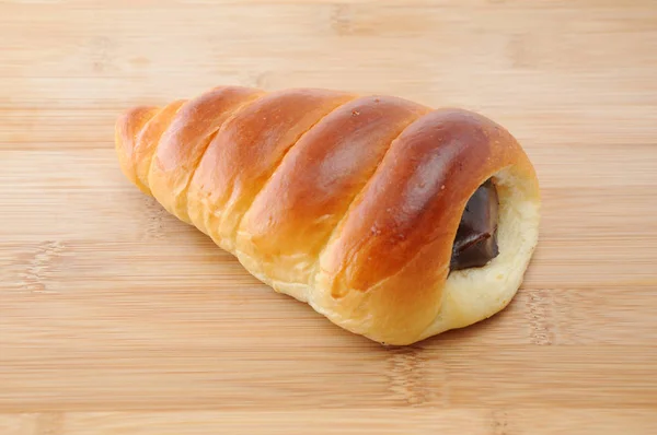 Rolo de pão de manteiga de corneto de chocolate na placa de corte — Fotografia de Stock