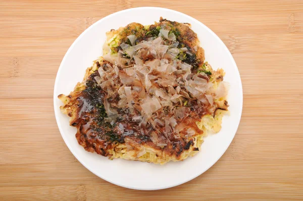 Okonomiyaki японская блинная еда на тарелке на столе — стоковое фото
