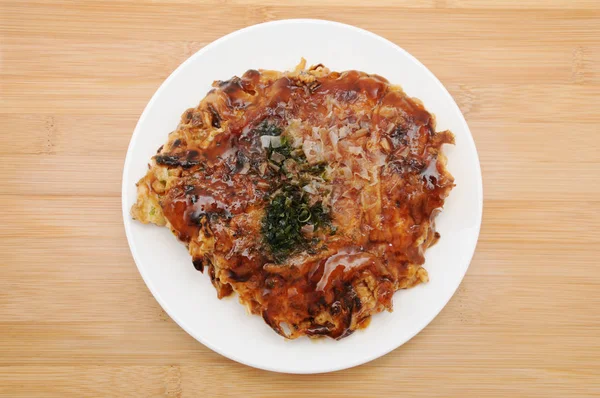 Okonomiyaki японская блинная еда на тарелке на столе — стоковое фото