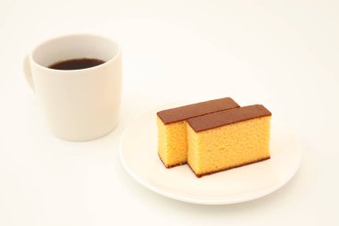 beyaz arka plan üzerinde sıcak kahve ile plaka üzerinde castella japon sünger kek