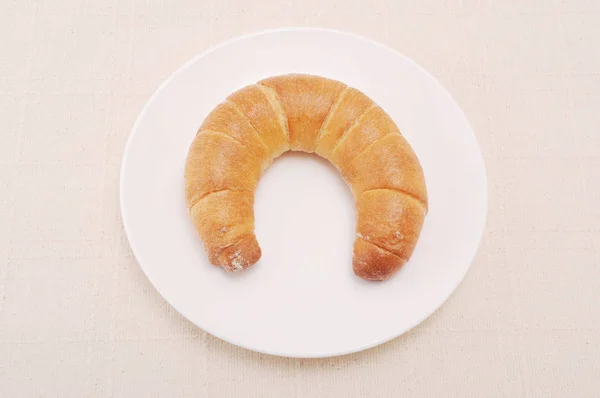 Pan francés del croissant del rollo creciente en el plato en el paño de tabla —  Fotos de Stock