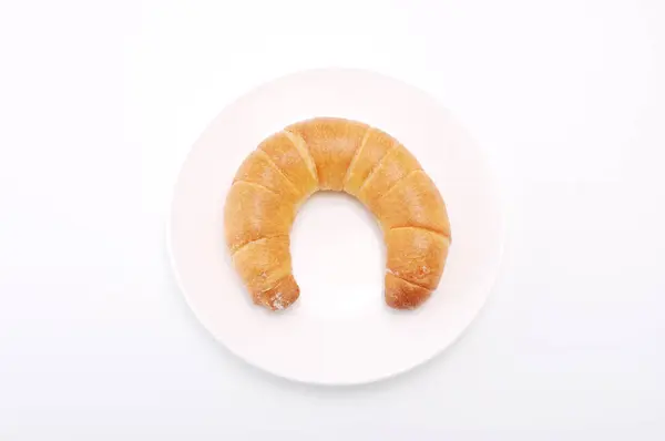Halvmånsvalsing av kryssfindig fransk brød på plate på hvit bakgrunn – stockfoto
