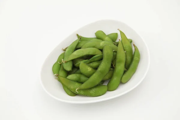 Зеленые соевые бобы edamame японская закуска на тарелке на белом фоне — стоковое фото