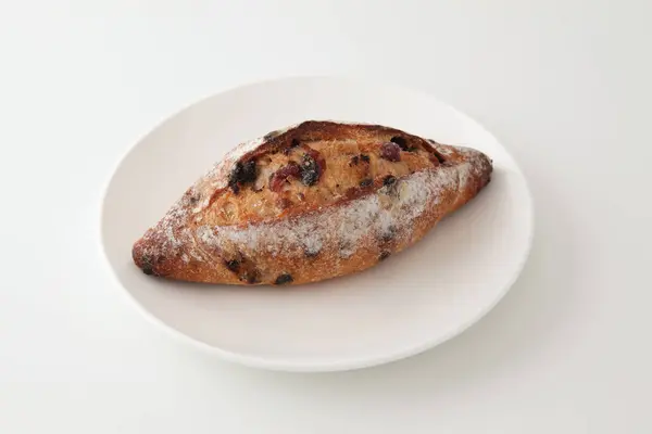 Pan francés con arándanos secos y chips de choco en el plato sobre fondo blanco — Foto de Stock