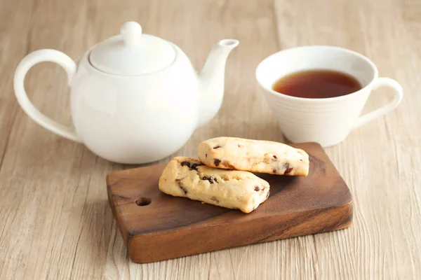 Scone de frutas secas com panela de chá e xícara de chá na mesa — Fotografia de Stock