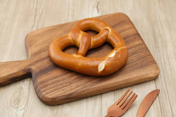 Krakeling Duits brood op houten plaat geïsoleerd op tafel — Stockfoto