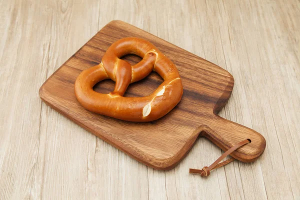 Precel niemiecki chleb na drewnianym talerzu izolowanym na stole — Zdjęcie stockowe