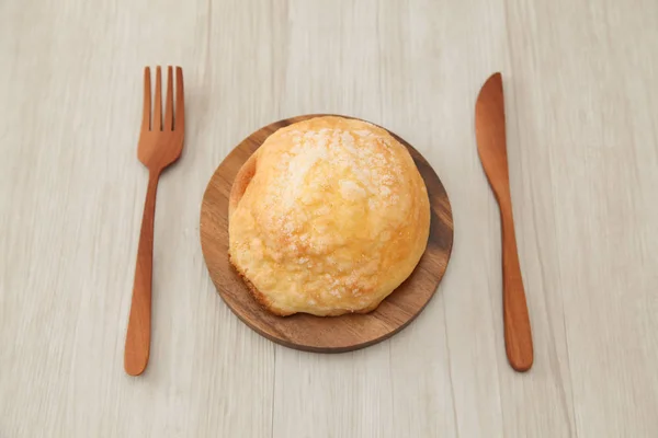 sugar bread melon pan on wood plate fork knife isolated on table