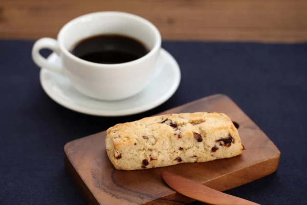 Biscoito de scone de frutas secas com uma xícara de café na mesa de madeira — Fotografia de Stock