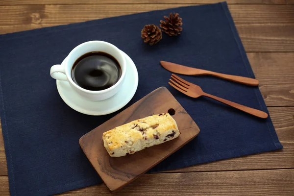 Biscoito de scone de frutas secas com uma xícara de café na mesa de madeira — Fotografia de Stock