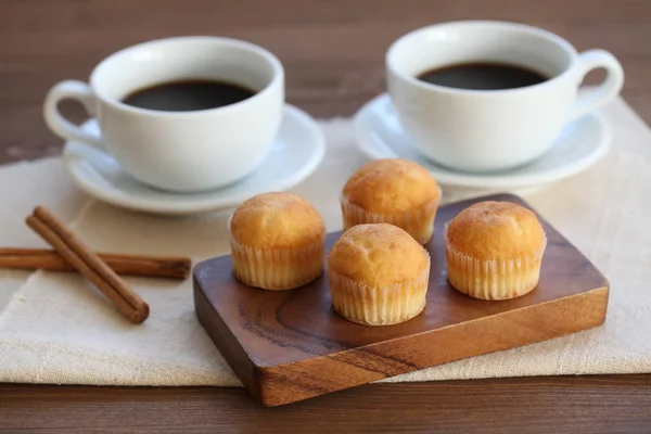 Magdalenas sobre mesa de madera con tazas de café — Foto de Stock