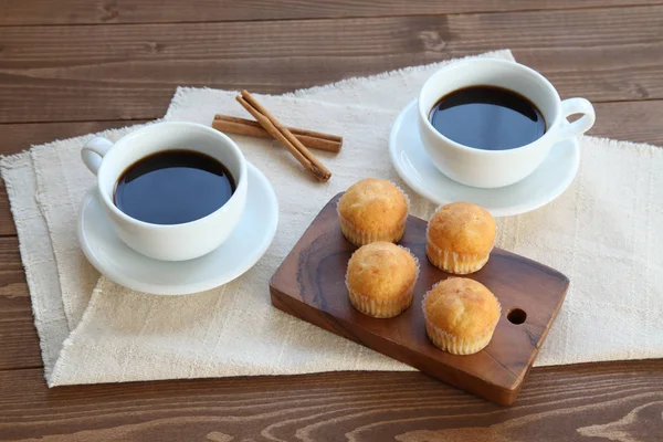 Cupcakes na mesa de madeira com xícaras de café — Fotografia de Stock