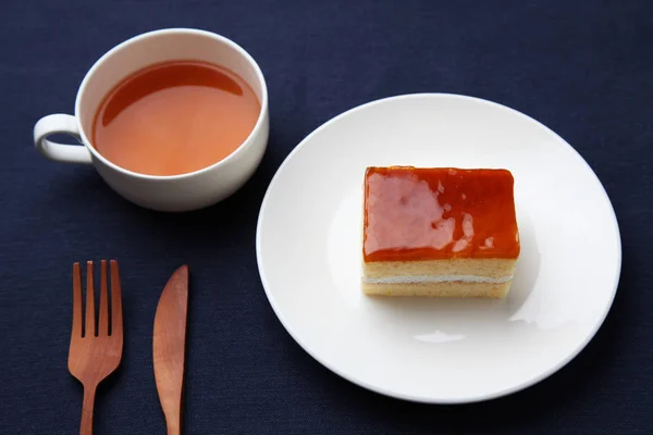 Torta di sciroppo di miele arancione sul piatto con tè caldo isolato sul tavolo — Foto Stock