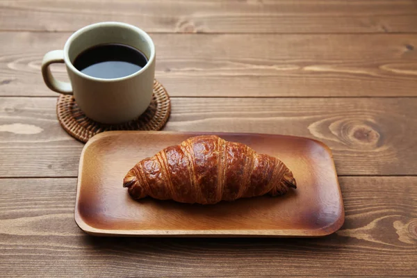 Croissant french bread on wood plate and hot coffee isolated on wood table — Stock Photo, Image