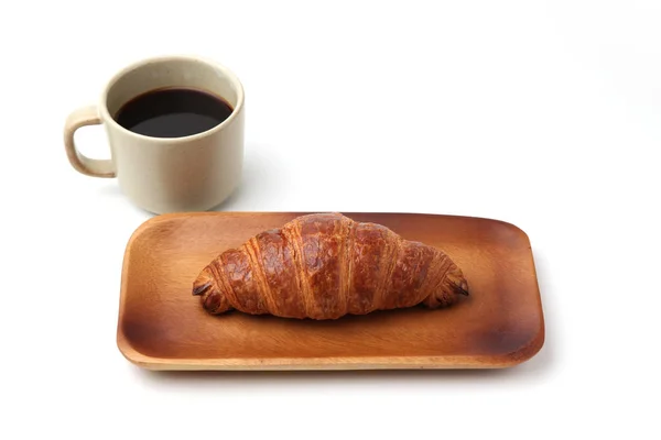 Круасан французький хліб на дерев'яній тарілці та гарячій каві ізольовані на білому тлі — стокове фото