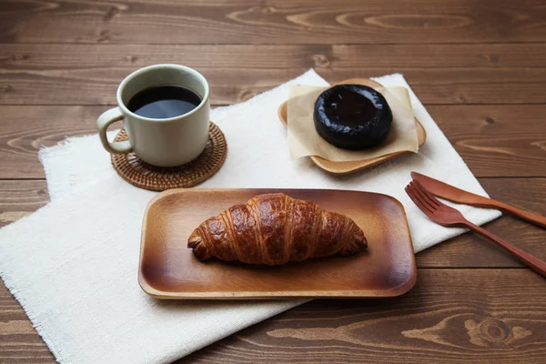 Croissant french bread on wood plate and hot coffee with dessert isolated on table — Stock Photo, Image