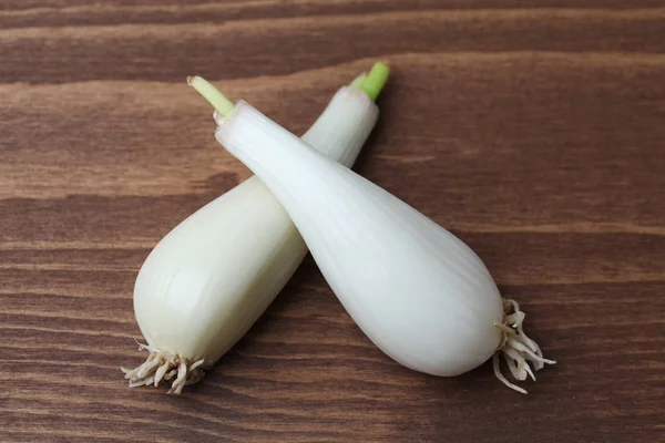 Rohe Zwiebeln von japanischem Porree chinesische Zwiebel isoliert auf Holztisch — Stockfoto