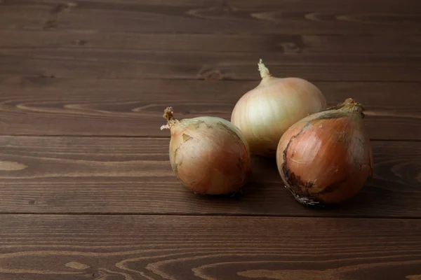 Cebollas crudas aisladas en mesa de madera —  Fotos de Stock