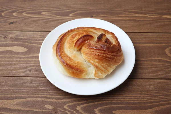 Round danish bread on plate isolated on wooden table — Stock Photo, Image