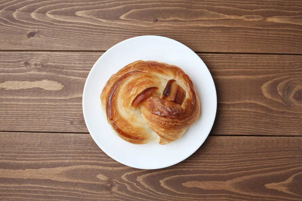 Pão dinamarquês redondo na placa isolada na mesa de madeira — Fotografia de Stock