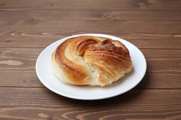 Pão dinamarquês redondo na placa isolada na mesa de madeira — Fotografia de Stock