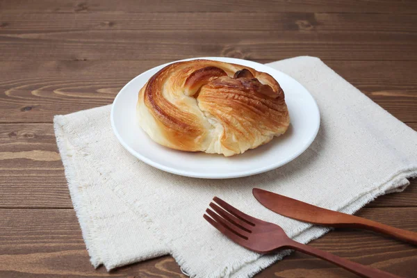 Round danish bread on plate isolated on wooden table — Stock Photo, Image