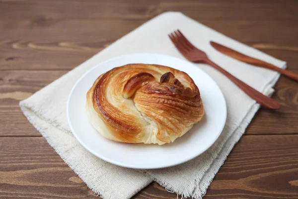 Round danish bread on plate isolated on wooden table — Stock Photo, Image