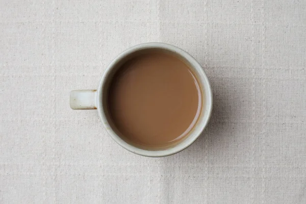 テーブルクロスの上に隔離された黒いホットミルクコーヒーのカップ — ストック写真