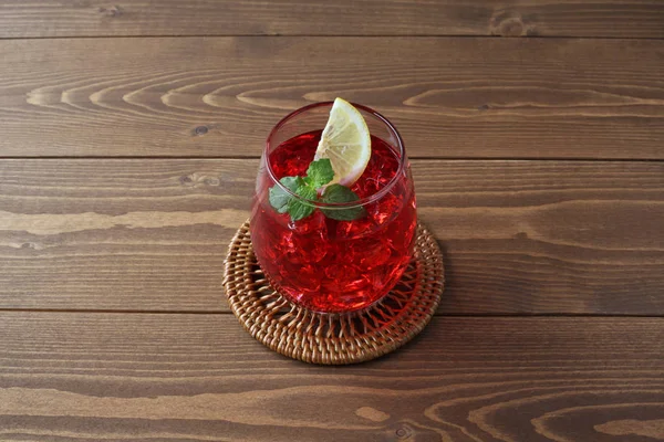 木製のテーブルの上に隔離された冷たい紅茶の赤い飲み物のグラス — ストック写真