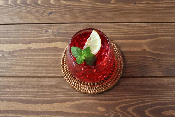木製のテーブルの上に隔離された冷たい紅茶の赤い飲み物のグラス — ストック写真
