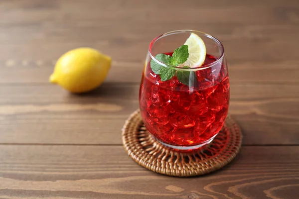 木製のテーブルの上に隔離されたレモンと冷たい紅茶の赤い飲み物のグラス — ストック写真
