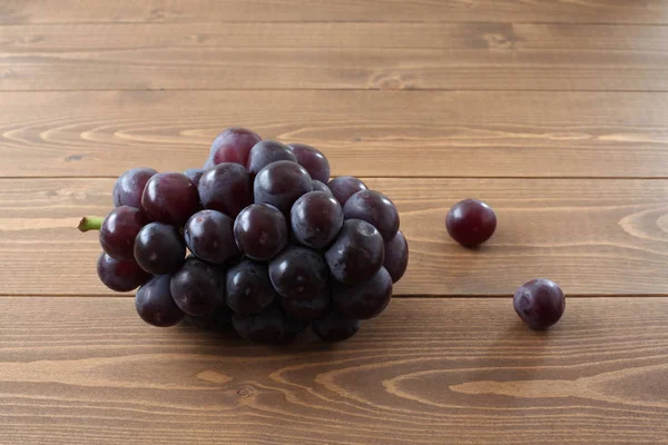 Cacho fresco de uvas isoladas na mesa de madeira — Fotografia de Stock