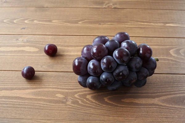 Fresh bunch of grapes isolated on wooden table — Stock Photo, Image