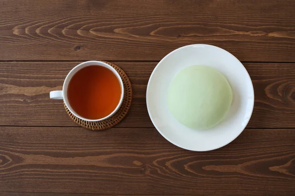 green round melon pan on plate with hot tea isolated  on wooden table