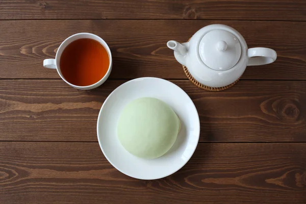 green round melon pan on plate with hot tea isolated  on wooden table