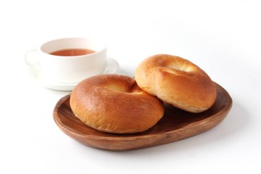 beyaz arka plan üzerinde sıcak çay ile ahşap tabak üzerinde düz simit ekmek