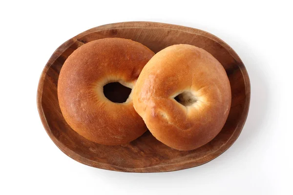 Gewone bagels brood op houten plaat op witte achtergrond — Stockfoto