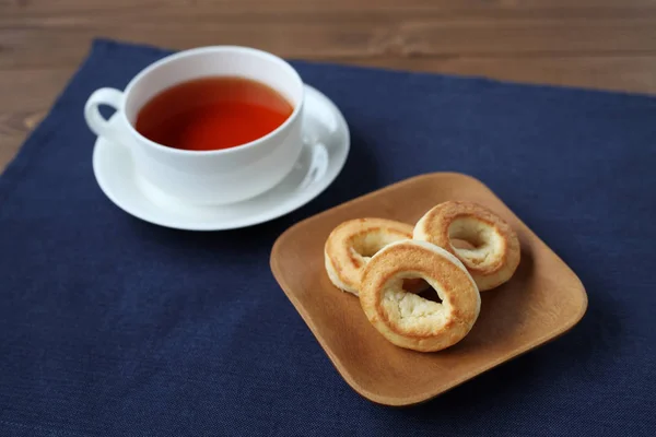 Ring scone biscuit on plate with hot tea isolated on table — Stock Photo, Image