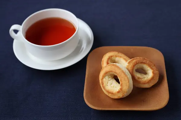 Anillo bollo de galletas en el plato con té caliente aislado en la mesa — Foto de Stock