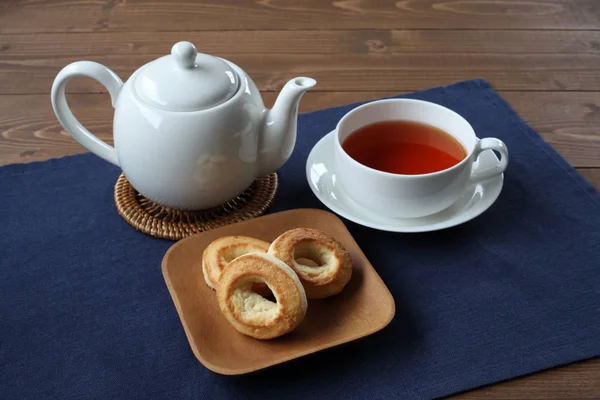 Anillo bollo de galletas en el plato con té caliente aislado en la mesa —  Fotos de Stock