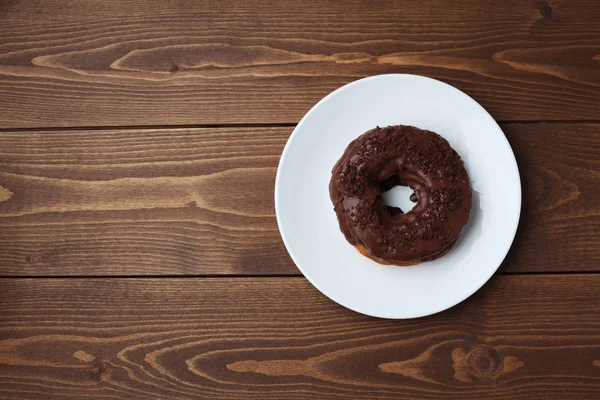 Пончик с шоколадной глазурью на деревянном столе — стоковое фото