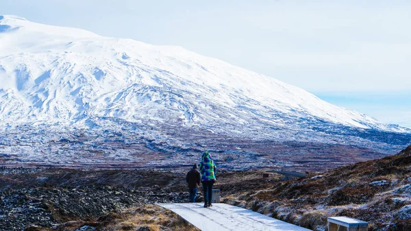 Tourist walk in Iceland volcanic landscape snow moutnian background